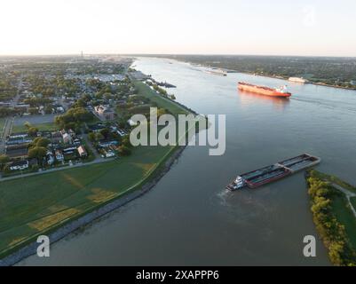 Aus der Vogelperspektive lässt ein Binnenschiff den Industriekanal in New Orleans' historischem 9th Ward verlassen und bei Sonnenaufgang in den Mississippi River eindringt. Stockfoto