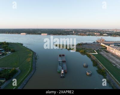 Aus der Vogelperspektive lässt ein Binnenschiff den Industriekanal in New Orleans' historischem 9th Ward verlassen und bei Sonnenaufgang in den Mississippi River eindringt. Stockfoto