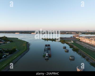 Aus der Vogelperspektive lässt ein Binnenschiff den Industriekanal in New Orleans' historischem 9th Ward verlassen und bei Sonnenaufgang in den Mississippi River eindringt. Stockfoto