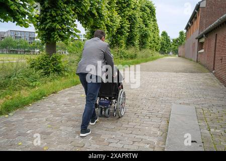 Mann schiebt Rollstuhl mit einer älteren Frau Stockfoto