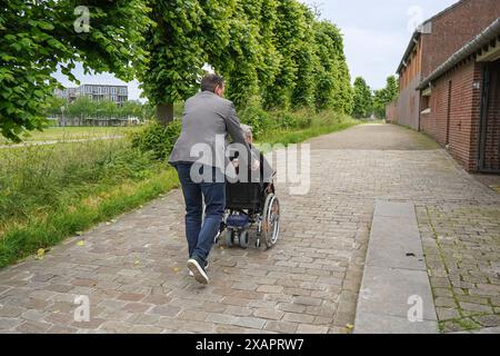 Mann schiebt Rollstuhl mit einer älteren Frau Stockfoto