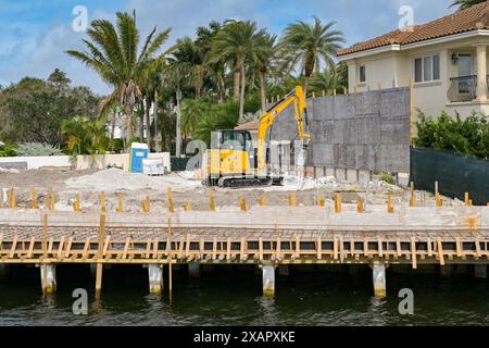 Fort Lauderdale, Florida, USA - 2. Dezember 2023: Kleiner Bagger arbeitet an den Fundamenten eines neuen Luxushauses auf einer Baustelle Stockfoto
