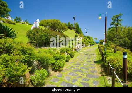 Donghae City, Südkorea - 18. Mai 2024: Ein friedlicher Steinweg gesäumt von üppigem Grün und künstlerischen Skulpturen im Isabu Lion Park & Picture Boo Stockfoto