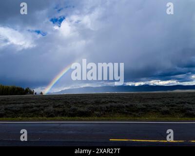 Regenbogen in einem bewölkten Himmel mit Bergen im Hintergrund Stockfoto