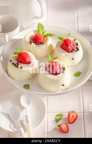 Hausgemachte Käsekuchen-Monoportion mit Beeren und Vanille. Erdbeer-Käsekuchen mit Vanille glasiert. Stockfoto