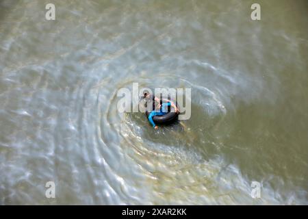 Dhaka, Bangladesch. Juni 2024. Öl ist aus einem Boot ausgelaufen, das am 8. Juni 2024 auf dem Buriganga River in Dhaka, Bangladesch, schwimmt. Trotz der Verschmutzung schwimmen zwei Menschen im verschmutzten Wasser in der Nähe. (Kreditbild: © Suvra Kanti das/ZUMA Press Wire) NUR REDAKTIONELLE VERWENDUNG! Nicht für kommerzielle ZWECKE! Stockfoto