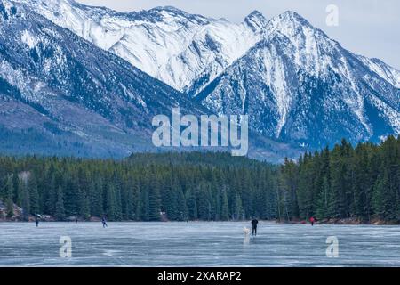 Johnson Lake gefrorene Wasseroberfläche im Winter. Schneebedeckter Berg im Hintergrund. Touristen hier, die in dieser Saison Schlittschuhlaufen. Banff Natio Stockfoto