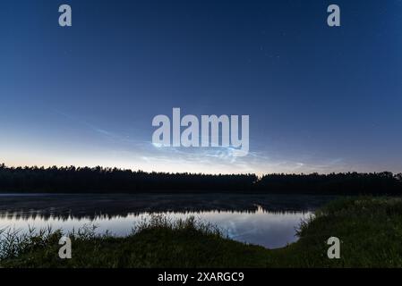 Nächtliche Wolken über dem Waldsee in Lettland in der Juninacht Stockfoto