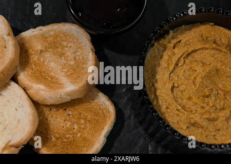 Pastete mit Soße und Croutons auf einem schwarzen Brett Stockfoto