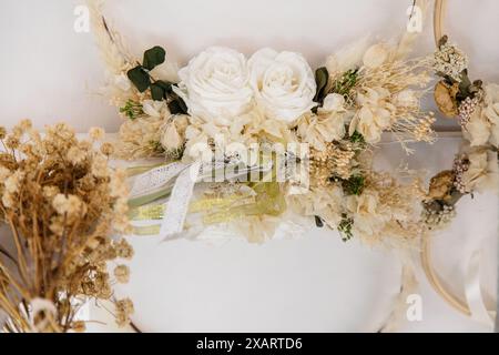 Wunderschön gearbeitete Blumenkränze mit weißen Rosen und getrockneten Blumen, elegant auf weißem Hintergrund angeordnet Stockfoto