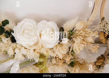 Wunderschön gearbeitete Blumenkränze mit weißen Rosen und getrockneten Blumen, elegant auf weißem Hintergrund angeordnet Stockfoto