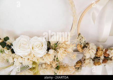 Wunderschön gearbeitete Blumenkränze mit weißen Rosen und getrockneten Blumen, elegant auf weißem Hintergrund angeordnet Stockfoto