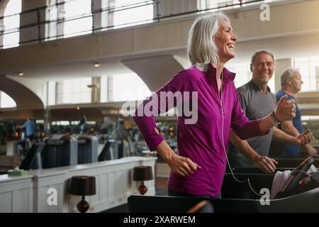 Bewegung, Laufband und Senioren laufen im Fitnessstudio für Workout, körperliche Gesundheit und Wellness im Ruhestand. Gruppen, Joggen oder gemeinsam trainieren Stockfoto
