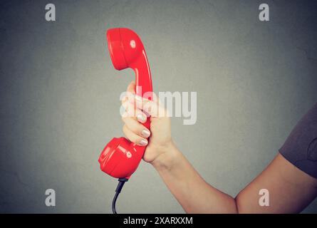 Nahaufnahme eines Mannes, der die Hand hält und den roten Telefonhörer zeigt. Stockfoto