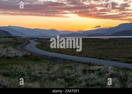 Fairbourne, Gwynedd, Wales, Großbritannien. April 2024. Sonnenaufgang mit Mawddach Mündung, Bergen und Barmouth Bridge im Blick Stockfoto