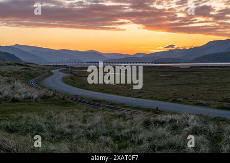 Fairbourne, Gwynedd, Wales, Großbritannien. April 2024. Sonnenaufgang mit Mawddach Mündung, Bergen und Barmouth Bridge im Blick Stockfoto