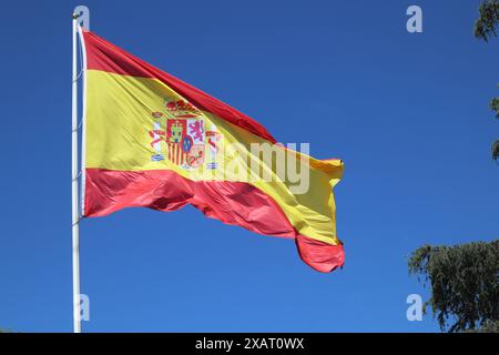 Die spanische Flagge flattert im Wind gegen einen blauen Himmel Stockfoto