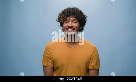 Studio-Porträt glücklicher arabischer Mann Indianer Guy Hispanic männlich auf Kopfhörer Musik hören Tanzen hören Radio singen auf blauem Hintergrund Stockfoto