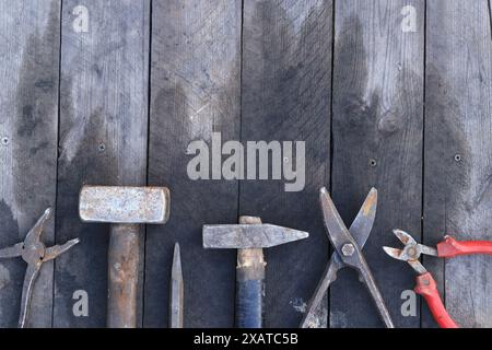 Alte Arbeitsgeräte auf einer Holzdiele, Draufsicht. Hämmer, Vorschlaghämmer, Metallscheren, Zangen und vieles mehr. Handwerkzeug. Bauertag oder Vatertag. C Stockfoto