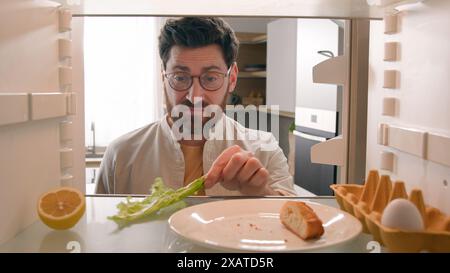 Blickwinkel von innen Kühlschrank POV Kaukasischer Erwachsener Hausbesitzer öffnen Kühlschranktür Küche riecht schrecklich riechender Kerl schlechtes Aroma Stockfoto
