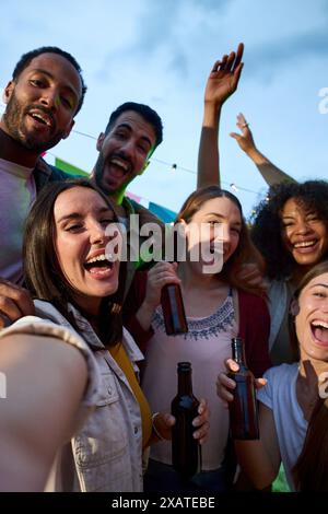 Fröhliche attraktive junge Frau, die Selfie bei der Millennial Alkohol Party Gruppe glücklich Multiracial nimmt Stockfoto