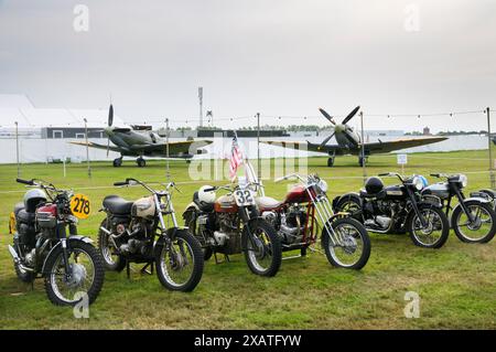 Classic Triumph Motorräder inkl. Amerikanisches Motorrad mit Stars and Stripes Flagge vor Kampfflugzeugen im Goodwood Revival UK Stockfoto