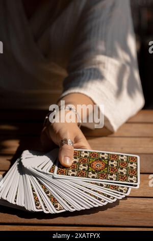 Eine Frau in einem leichten Outfit liest Tarotkarten auf einem Tisch in einem Café Stockfoto