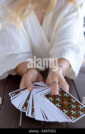 Eine Frau in einem leichten Outfit liest Tarotkarten auf einem Tisch in einem Café Stockfoto