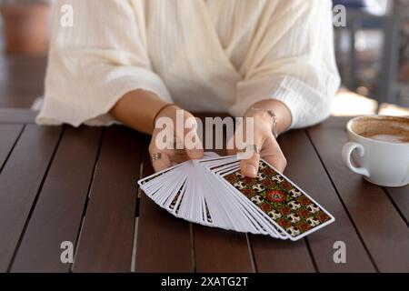 Eine Frau in einem leichten Outfit liest Tarotkarten auf einem Tisch in einem Café Stockfoto