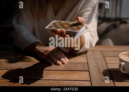 Eine Frau in einem leichten Outfit liest Tarotkarten auf einem Tisch in einem Café Stockfoto