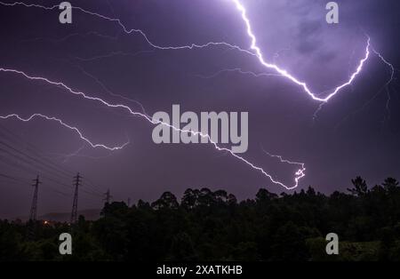 Gewitternacht mit mehreren Strahlen am Himmel über der Baumlinie am Horizont. Stockfoto