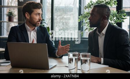 Zwei verschiedene Geschäftsleute, multirassische Männer im Büro mit Laptop. Kaukasischer Finanzberater Manager Berater Versicherungsagent Beratung Afrikaner Stockfoto