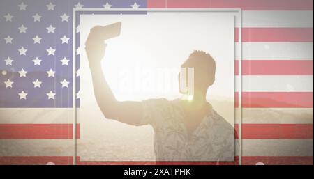 Amerikanische Flagge mit Störeffekt gegen afroamerikaner, der am Strand ein Selfie macht Stockfoto