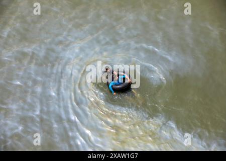 Dhaka, Bangladesch. Juni 2024. Öl ist von einem Boot, das auf dem Buriganga River in Dhaka, Bangladesch schwimmt, ausgelaufen. Trotz der Verschmutzung schwimmen zwei Menschen im verschmutzten Wasser in der Nähe. (Kreditbild: © Suvra Kanti das/ZUMA Press Wire) NUR REDAKTIONELLE VERWENDUNG! Nicht für kommerzielle ZWECKE! Stockfoto