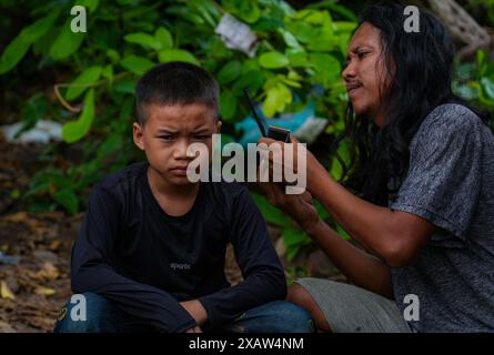 Ein Freiwilliger wird gesehen, wie er dem Kind aus dem Flüchtlingslager die Haare schneidet. Flüchtlinge aus dem Bürgerkrieg in Myanmar haben in der Nähe der Grenze zu Thailand Zuflucht gefunden. Die Armee Myanmars hat Mörserangriffe und Luftangriffe auf Rebellenpositionen und zivile Siedlungen eingeleitet. Southern Territory Supportive Organization ist eine freiwillige medizinische Team-Organisation, die im August 2021 gegründet wurde. Sie gewährten VERTRIEBENEN, Kriegsflüchtlingen, Wanderarbeitern, revolutionären Kräften und Dörfern unter der Kontrolle der ethnischen Revolutionären Organisation kostenlose medizinische Behandlung. Sie gehen jedes Wochenende an diese Orte. T Stockfoto