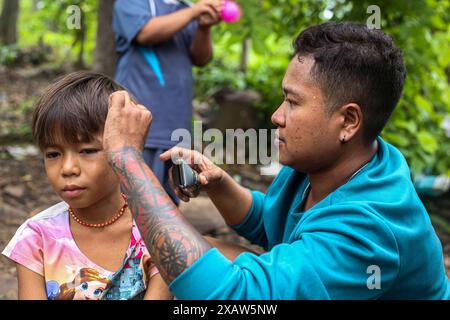 Ein Freiwilliger wird gesehen, wie er dem Kind aus dem Flüchtlingslager die Haare schneidet. Flüchtlinge aus dem Bürgerkrieg in Myanmar haben in der Nähe der Grenze zu Thailand Zuflucht gefunden. Die Armee Myanmars hat Mörserangriffe und Luftangriffe auf Rebellenpositionen und zivile Siedlungen eingeleitet. Southern Territory Supportive Organization ist eine freiwillige medizinische Team-Organisation, die im August 2021 gegründet wurde. Sie gewährten VERTRIEBENEN, Kriegsflüchtlingen, Wanderarbeitern, revolutionären Kräften und Dörfern unter der Kontrolle der ethnischen Revolutionären Organisation kostenlose medizinische Behandlung. Sie gehen jedes Wochenende an diese Orte. T Stockfoto