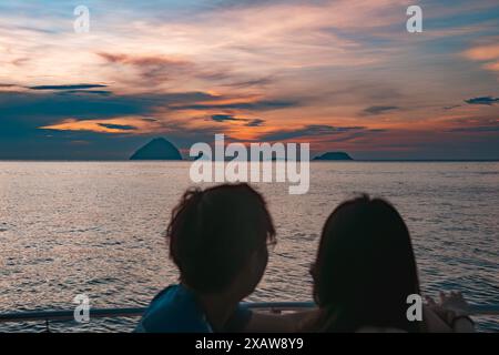 Perhentian, Kelatan, Malaysia - 9. Mai 2024 : Silhouette von zwei Menschen mit Blick auf das Meer mit Sonnenuntergang im Hintergrund Stockfoto