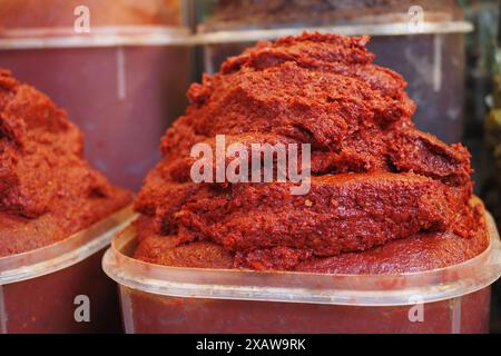 Beobachten Sie die detaillierte Ansicht der Behälter, die mit roter Pfefferpaste gefüllt sind, die auf einem lokalen Markt erhältlich sind Stockfoto