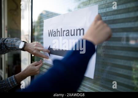 Duisburg, Deutschland. Juni 2024. Die Wahlhelfer hängen ein Blatt Papier auf, auf dem "Wahlraum" steht. Die Wahl zum Europäischen Parlament beginnt am 6. Juni. In Deutschland findet die Abstimmung am 9. Juni statt. Quelle: Fabian Strauch/dpa/Alamy Live News Stockfoto