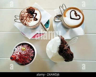Zwei Cappuccinos mit Dekoration und ein Zitronen- und Schokoladeneis. Stockfoto