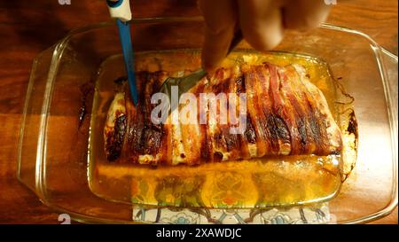 Ein Stück Schweinefilet aus dem Ofen, in Streifen Speck gewickelt. Stockfoto