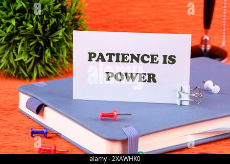 Konzeptworte GEDULD IST DIE LEISTUNG einer Visitenkarte, die auf einem Business-Notebook steht Stockfoto