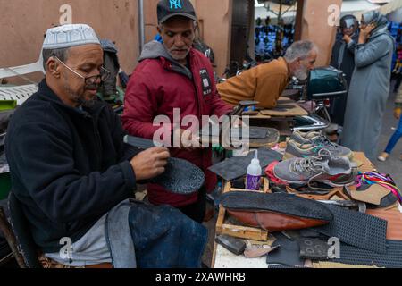 Marrakesch, Marokko - 23. März 2024: Traditionelle Schuhmacher im Souk der Medina von Marrakesch kleben neue Sohlen auf alte Schuhe Stockfoto