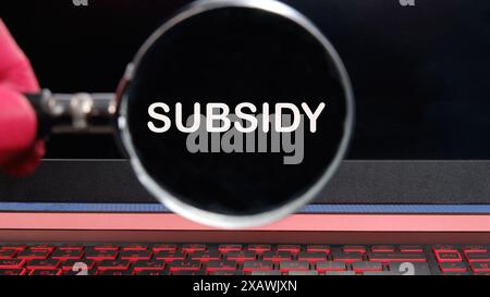Geschäftskonzept. SUBVENTIONSTEXT erschien durch eine Lupe auf einem dimmeren Laptop-Bildschirm Stockfoto