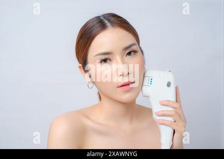 Schöne junge asiatische Frau, die sich einer Laser-HIFU-Behandlung in der Beauty Clinic unterzieht Stockfoto