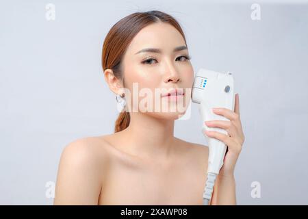 Charmante asiatische Frau mit Laser-HIFU-Werkzeug für die Hautstraffung Stockfoto