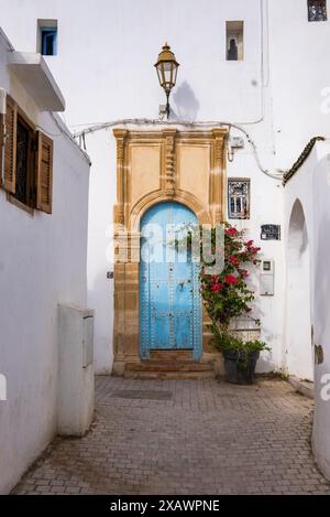 Typische weiße Straße mit einer bunten blauen Tür in der Kasbah der Oudayas in Rabat, Marokko. Die Stadt gehört zum UNESCO-Weltkulturerbe Stockfoto