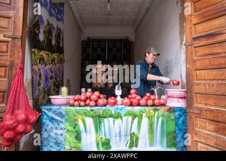 Ein Granatapfelsaftverkäufer halbiert einen Granatapfel, um in seinem Straßengeschäft in Rabat, der Hauptstadt Marokkos, Saft zu machen Stockfoto