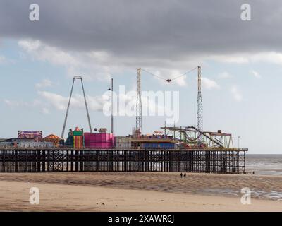 Touristen an einem Sandstrand am Amusement Park Pier in der Stadt Blackpool, Lancashire, England. Juni 2024 Stockfoto