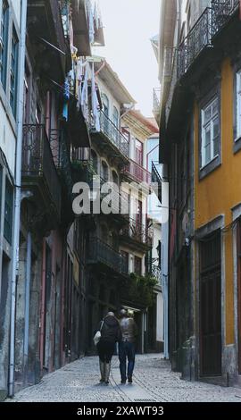 Ein paar spazieren durch eine charmante Gasse in Porto, über der Wäsche hängt Stockfoto